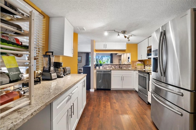 kitchen featuring stainless steel appliances, light stone countertops, a textured ceiling, white cabinets, and dark hardwood / wood-style flooring