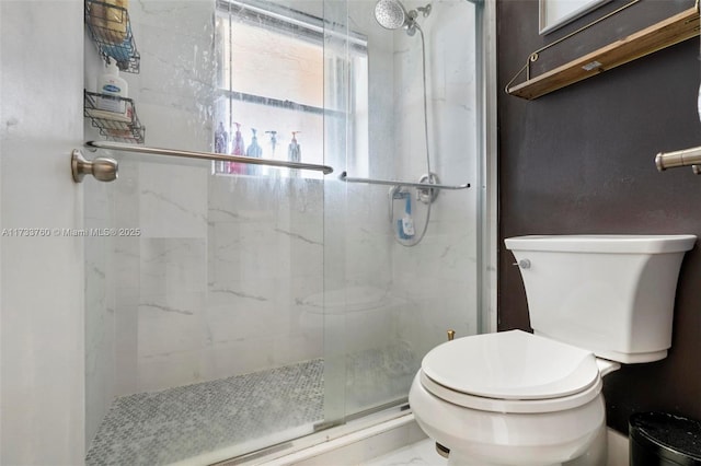 bathroom featuring a shower with door and toilet