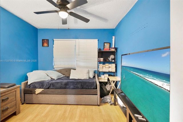 bedroom with a textured ceiling, light hardwood / wood-style floors, and ceiling fan