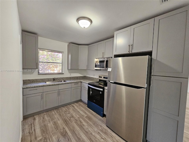 kitchen featuring light hardwood / wood-style flooring, sink, gray cabinets, and appliances with stainless steel finishes