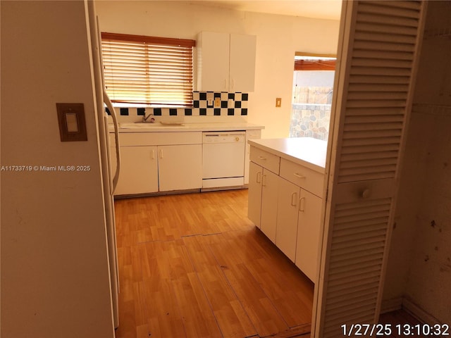 kitchen with a healthy amount of sunlight, dishwasher, light hardwood / wood-style floors, and white cabinets