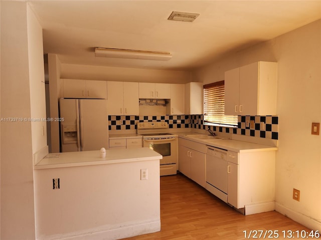 kitchen with sink, white appliances, light hardwood / wood-style flooring, white cabinetry, and backsplash