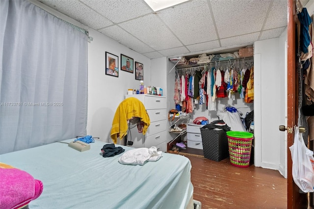 bedroom with hardwood / wood-style floors, a paneled ceiling, and a closet