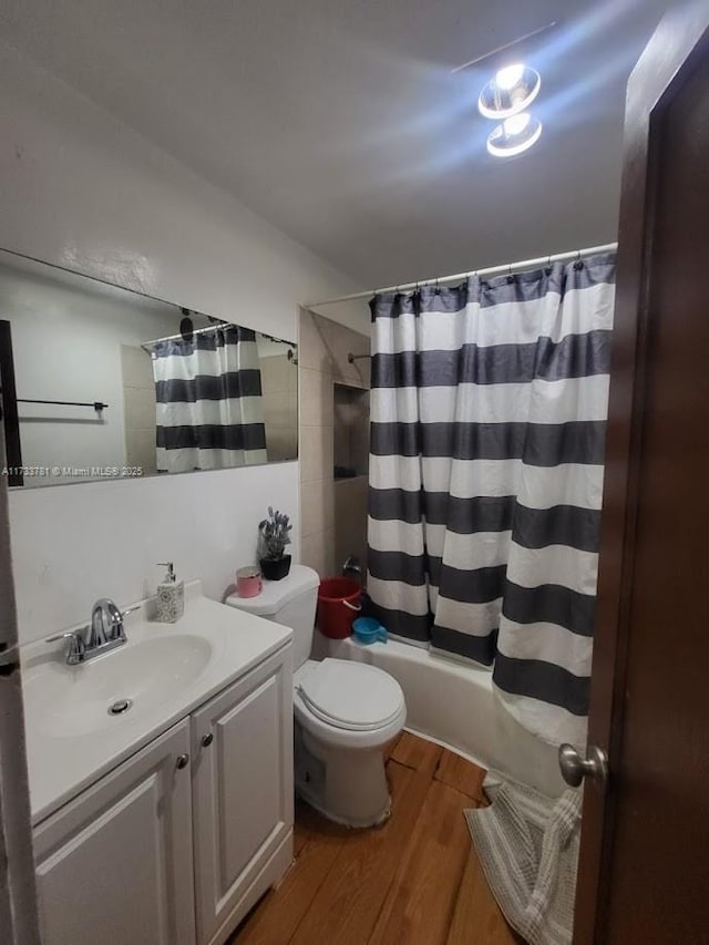 full bathroom featuring hardwood / wood-style flooring, vanity, toilet, and shower / bath combo with shower curtain