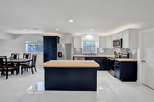 kitchen with wooden counters, appliances with stainless steel finishes, white cabinetry, a center island, and blue cabinets