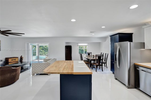 kitchen featuring butcher block counters, a wealth of natural light, stainless steel appliances, and blue cabinetry