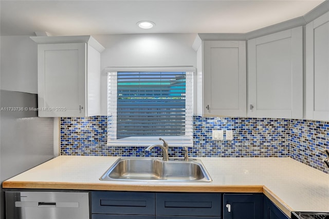 kitchen featuring tasteful backsplash, sink, dishwasher, and blue cabinets