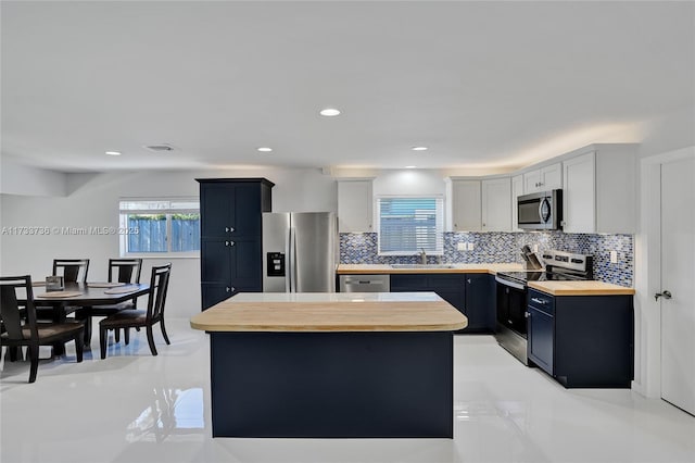 kitchen with stainless steel appliances, white cabinetry, a center island, and sink