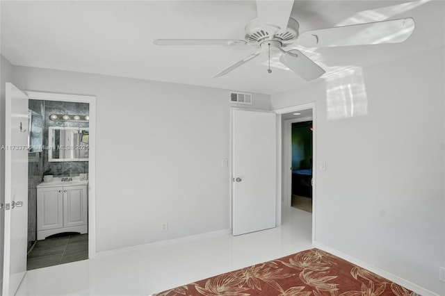 unfurnished bedroom with ceiling fan, light tile patterned flooring, and ensuite bath