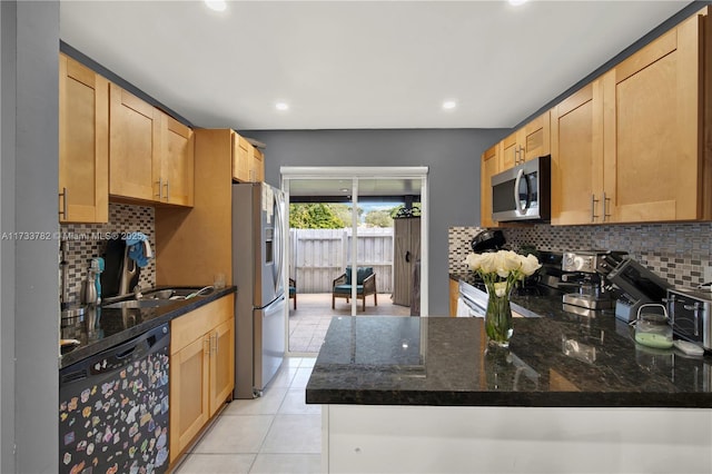 kitchen featuring light tile patterned flooring, appliances with stainless steel finishes, dark stone countertops, decorative backsplash, and kitchen peninsula