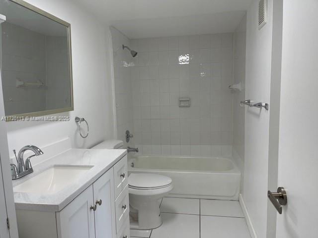 full bathroom with tile patterned flooring, vanity, tiled shower / bath, and toilet