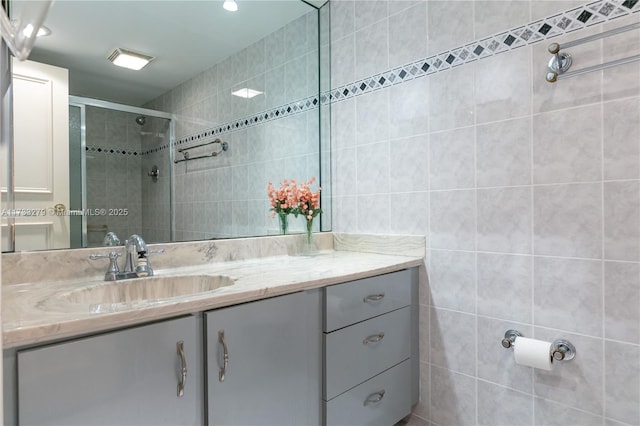 bathroom with vanity, tile walls, and a shower with shower door