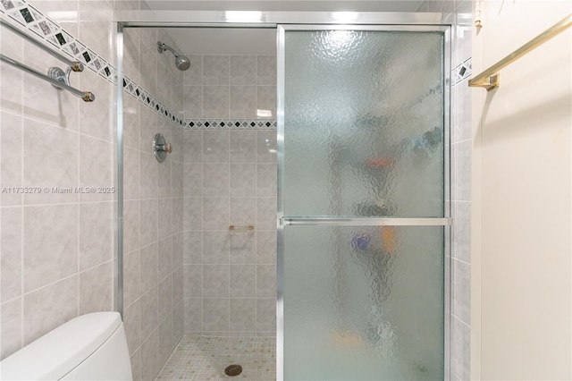 bathroom featuring a shower with door and toilet