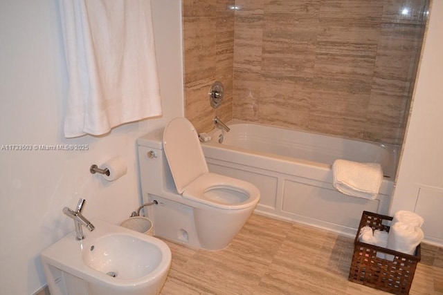 full bathroom featuring a bidet, sink, bathtub / shower combination, and toilet