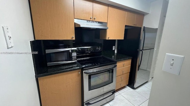 kitchen with dark stone countertops, stainless steel appliances, and light tile patterned floors