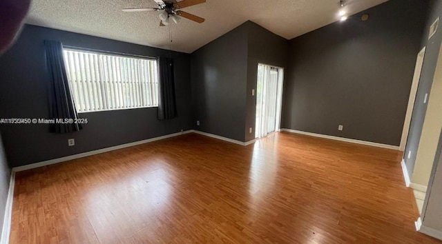 unfurnished room with vaulted ceiling, hardwood / wood-style floors, ceiling fan, and a textured ceiling