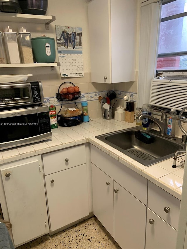 kitchen featuring sink, white cabinetry, backsplash, cooling unit, and tile countertops