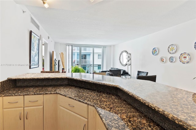 kitchen featuring light brown cabinetry, kitchen peninsula, and a textured ceiling