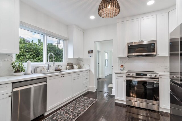 kitchen with white cabinetry, hanging light fixtures, appliances with stainless steel finishes, dark hardwood / wood-style flooring, and kitchen peninsula