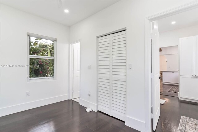 washroom with cabinets, stacked washer and clothes dryer, dark hardwood / wood-style floors, and a wealth of natural light