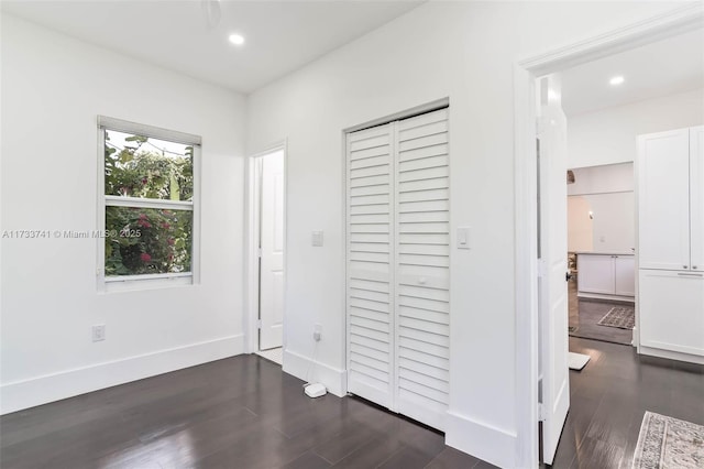 unfurnished bedroom with ensuite bath, dark hardwood / wood-style flooring, and a closet