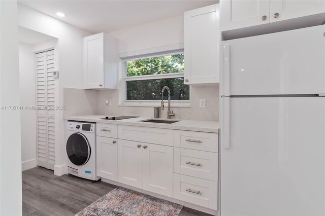 washroom featuring sink, wood-type flooring, and washer / clothes dryer