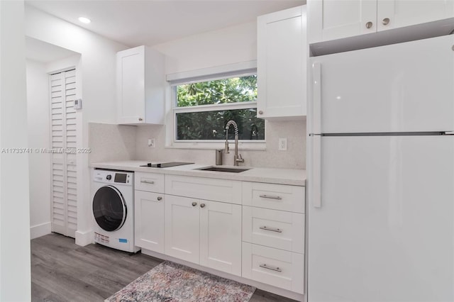 interior space with washer / clothes dryer, white cabinetry, tasteful backsplash, sink, and white fridge