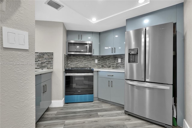 kitchen featuring decorative backsplash, stainless steel appliances, and light wood-type flooring