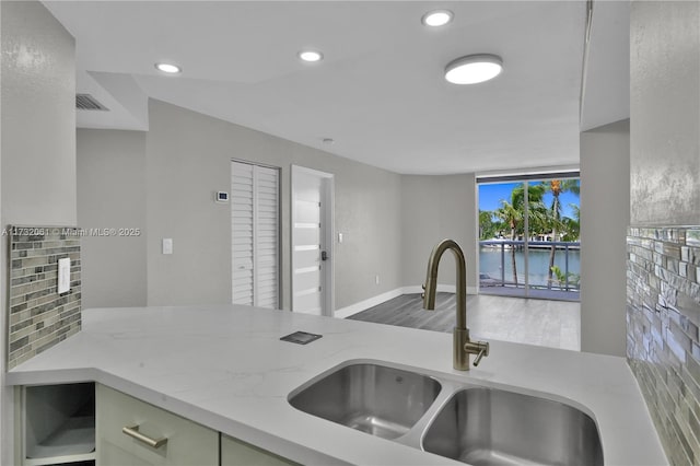 kitchen featuring light stone counters, sink, a wall of windows, and a water view