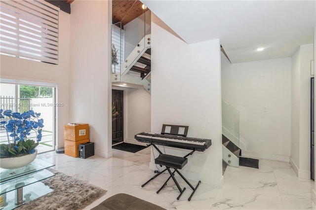 interior space featuring marble finish floor, stairs, a high ceiling, and baseboards