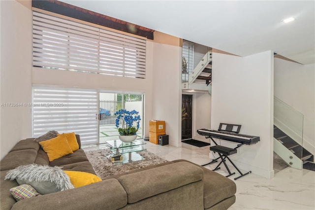 living room with marble finish floor, a towering ceiling, baseboards, and stairs