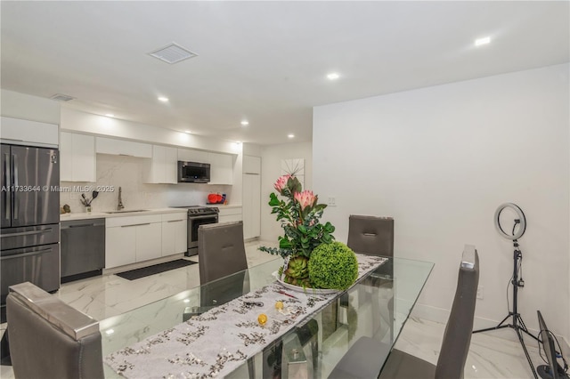 kitchen with visible vents, white cabinets, appliances with stainless steel finishes, marble finish floor, and a sink