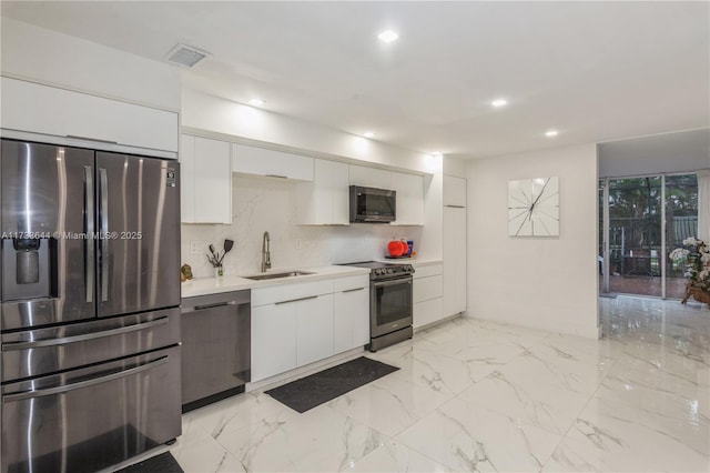 kitchen featuring appliances with stainless steel finishes, marble finish floor, white cabinets, and a sink