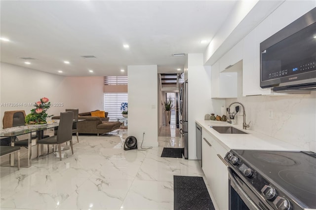 kitchen with stainless steel appliances, a sink, visible vents, white cabinetry, and marble finish floor