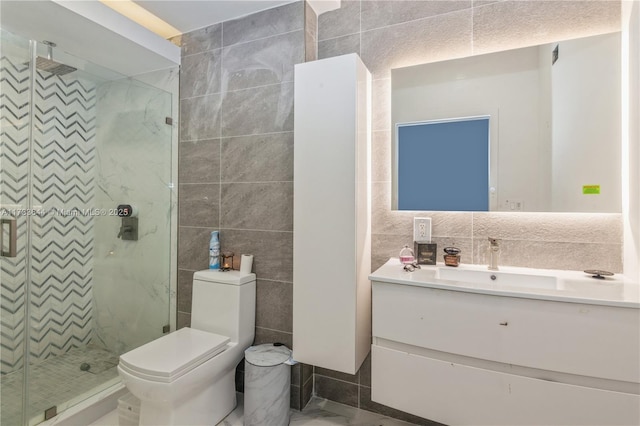 bathroom featuring marble finish floor, tile walls, toilet, a shower stall, and vanity