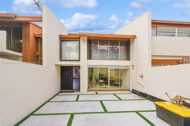 back of property featuring a patio area and stucco siding