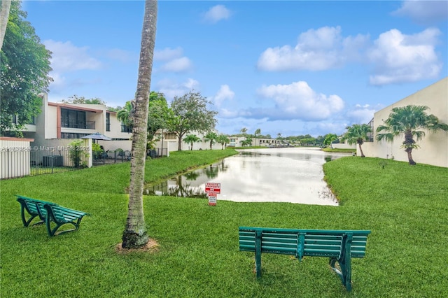 view of community with a water view, fence, and a lawn