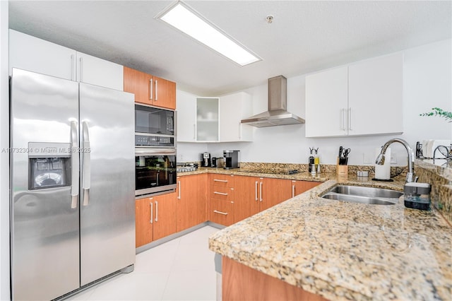 kitchen featuring wall chimney range hood, black appliances, sink, and white cabinets