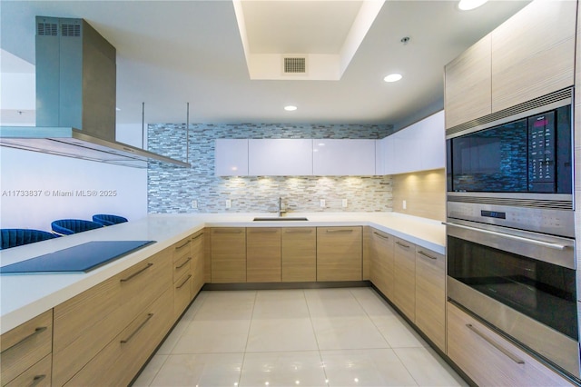 kitchen with sink, backsplash, stainless steel appliances, island range hood, and light brown cabinetry