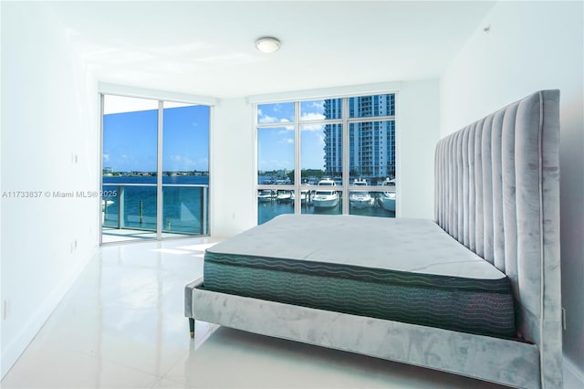 bedroom with expansive windows, a water view, and access to exterior