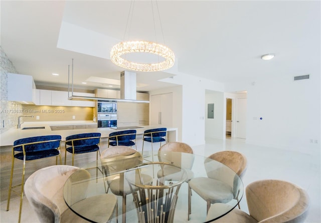 dining area with sink, a notable chandelier, and electric panel