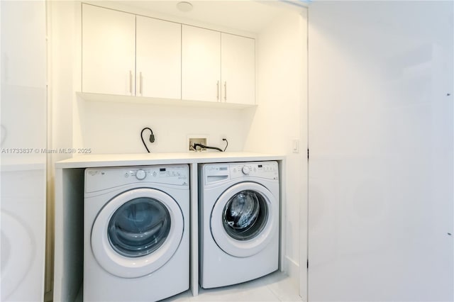 clothes washing area featuring light tile patterned floors, washer and clothes dryer, and cabinets