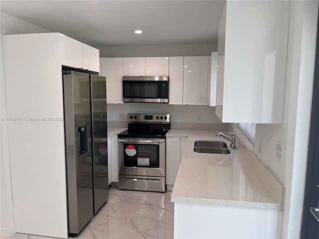 kitchen with appliances with stainless steel finishes, sink, and white cabinets