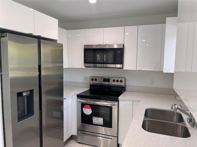 kitchen featuring light stone countertops, appliances with stainless steel finishes, sink, and white cabinets