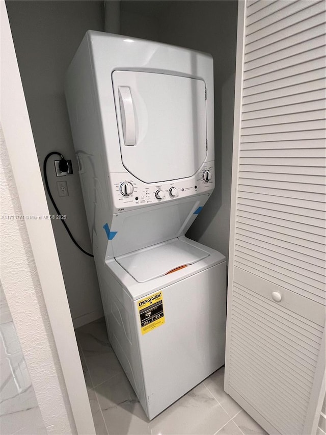 laundry room featuring stacked washer and clothes dryer and light tile patterned floors