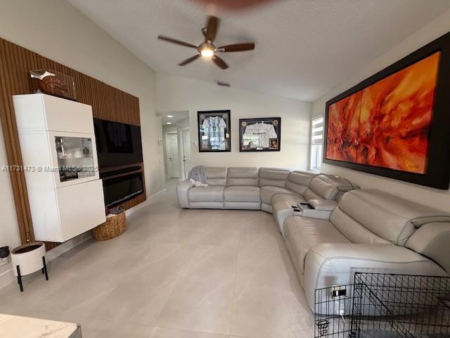 living room featuring lofted ceiling, a textured ceiling, and ceiling fan