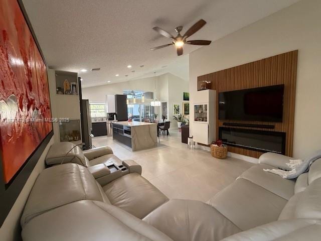 living room with ceiling fan, a fireplace, vaulted ceiling, and a textured ceiling