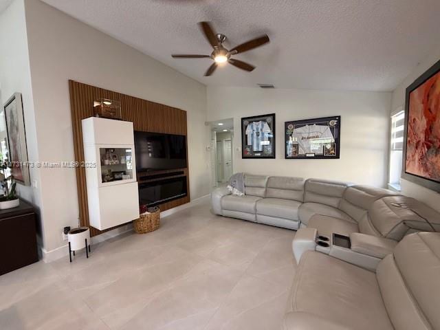 living room featuring ceiling fan, lofted ceiling, and a textured ceiling