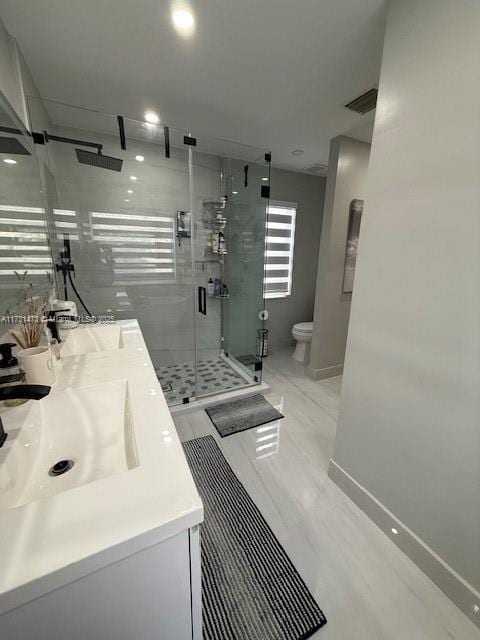 bathroom featuring a shower with door, vanity, and toilet