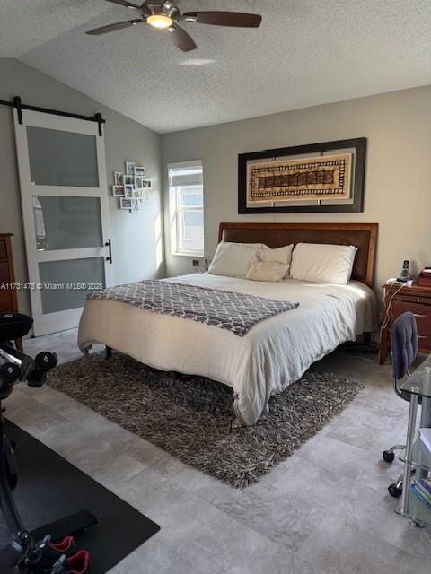 bedroom with lofted ceiling, ceiling fan, a barn door, and a textured ceiling